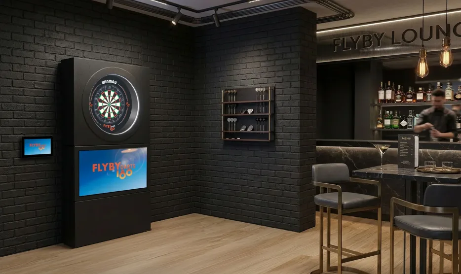 The FLYBY Darts turnkey rig, a matt-black cabinet with the screen above the board, in a dark bar