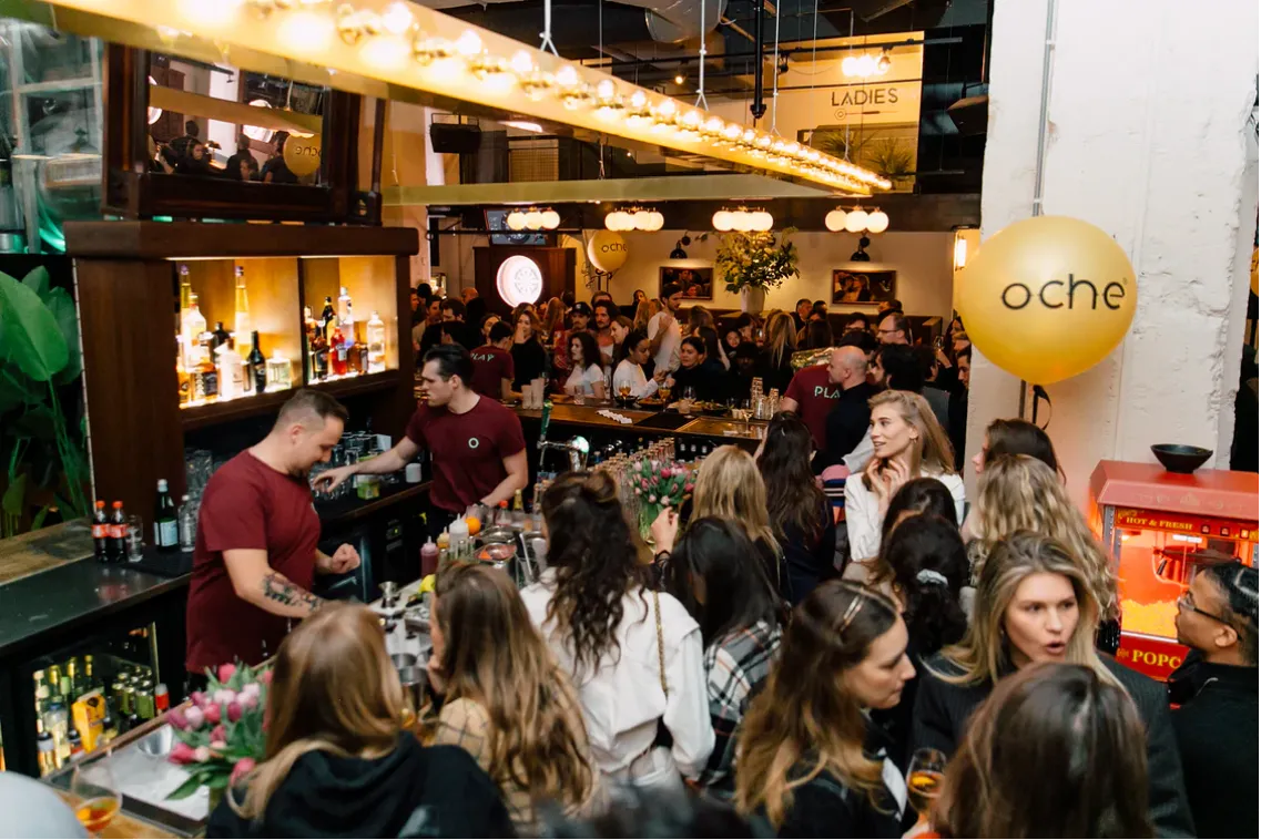 A crowded OCHE venue, the gold oche balloon above the bar