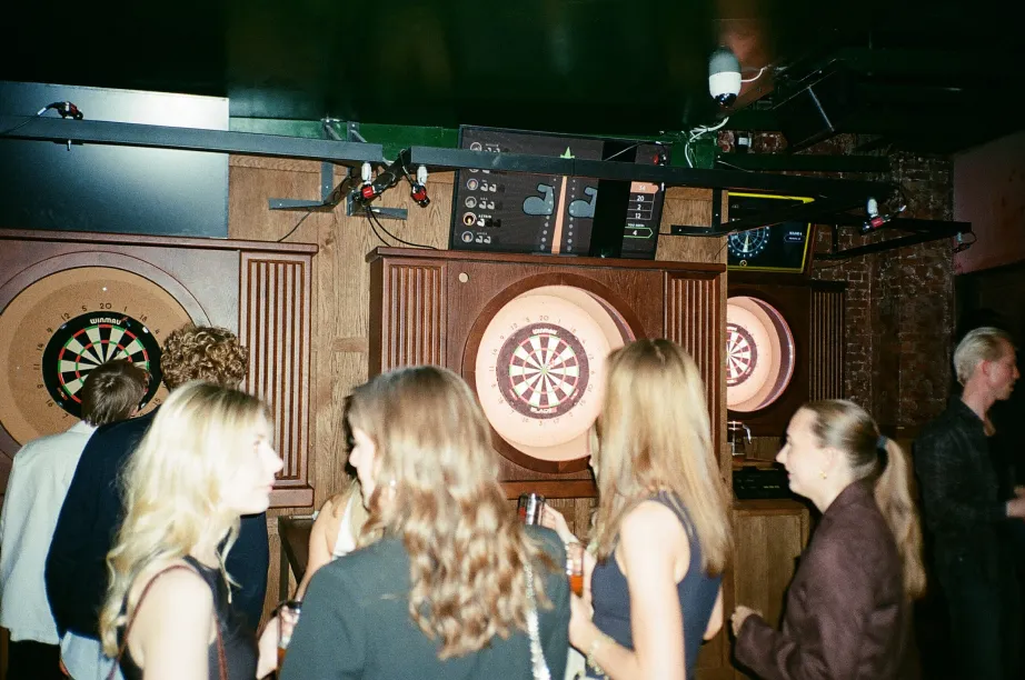 Guests gathered around the lit dartboards of an OCHE Experience Zone