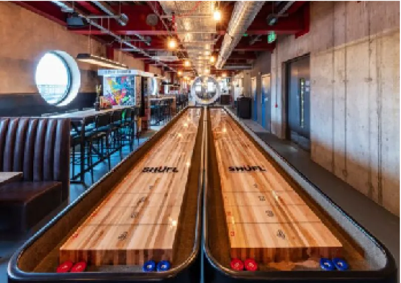 Two Grand Champion shuffleboard tables side by side in a bar
