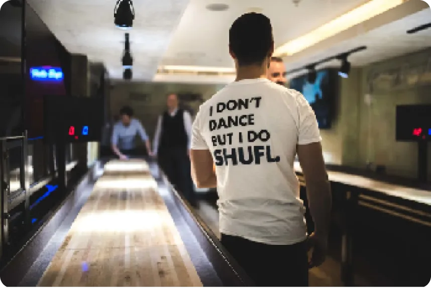 A player walking back from a SHUFL. table wearing an "I don't dance but I do SHUFL" T-shirt