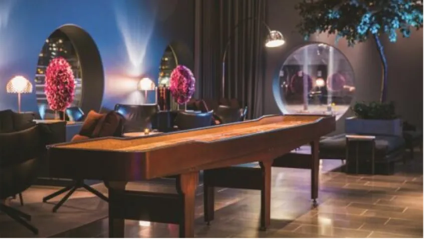 A SHUFL. curved shuffleboard table in a softly lit hotel lounge