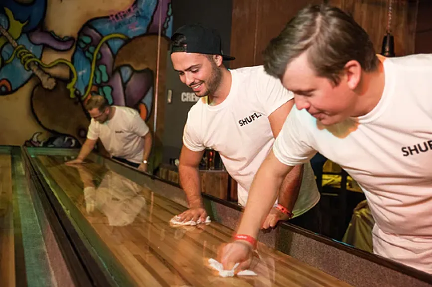 A TSGG team member preparing a shuffleboard playing surface during an installation